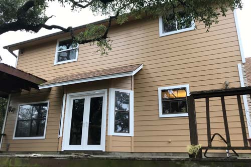 Close up of dark red brick and white panel siding of house.